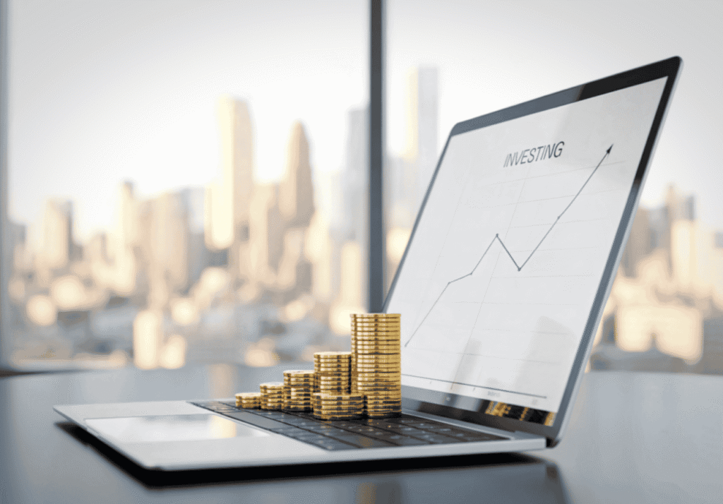 Laptop showing an investing growth chart with stacked coins symbolizing automated RRSP and TFSA contributions.