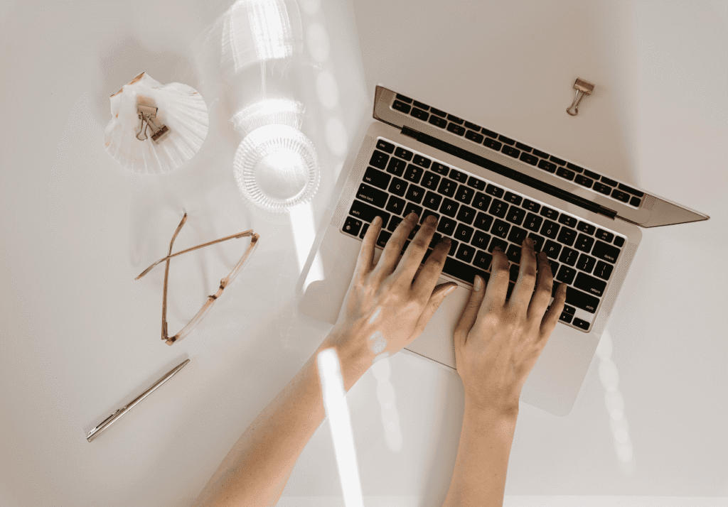 Hands typing on a laptop at a clean workspace, representing the Canadian finance team behind Growing Wealth.