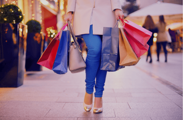 Woman carrying colourful shopping bags during the holidays on a city street.