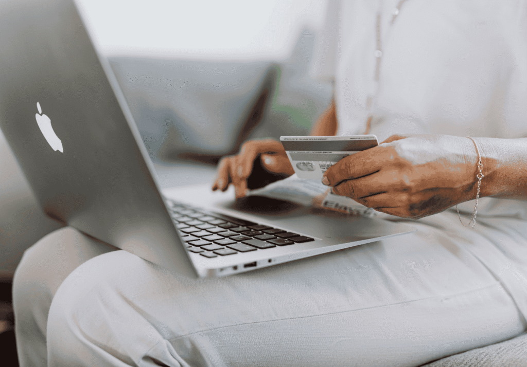 Person using a credit card while shopping online on a laptop, representing everyday family spending with a no-fee credit card.
