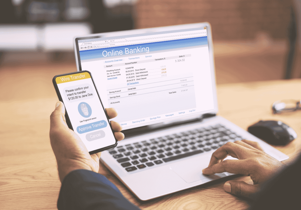 Person using online banking on a laptop and phone to manage chequing account and transfers.