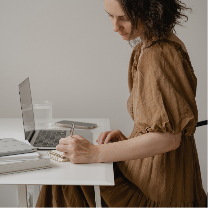 Woman reviewing financial notes at laptop as part of a larger family finance plan in Canada.