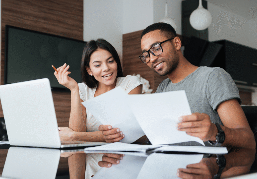 A couple reviewing financial documents together at a table, illustrating decisions about how to hold RRSP savings in Canada.