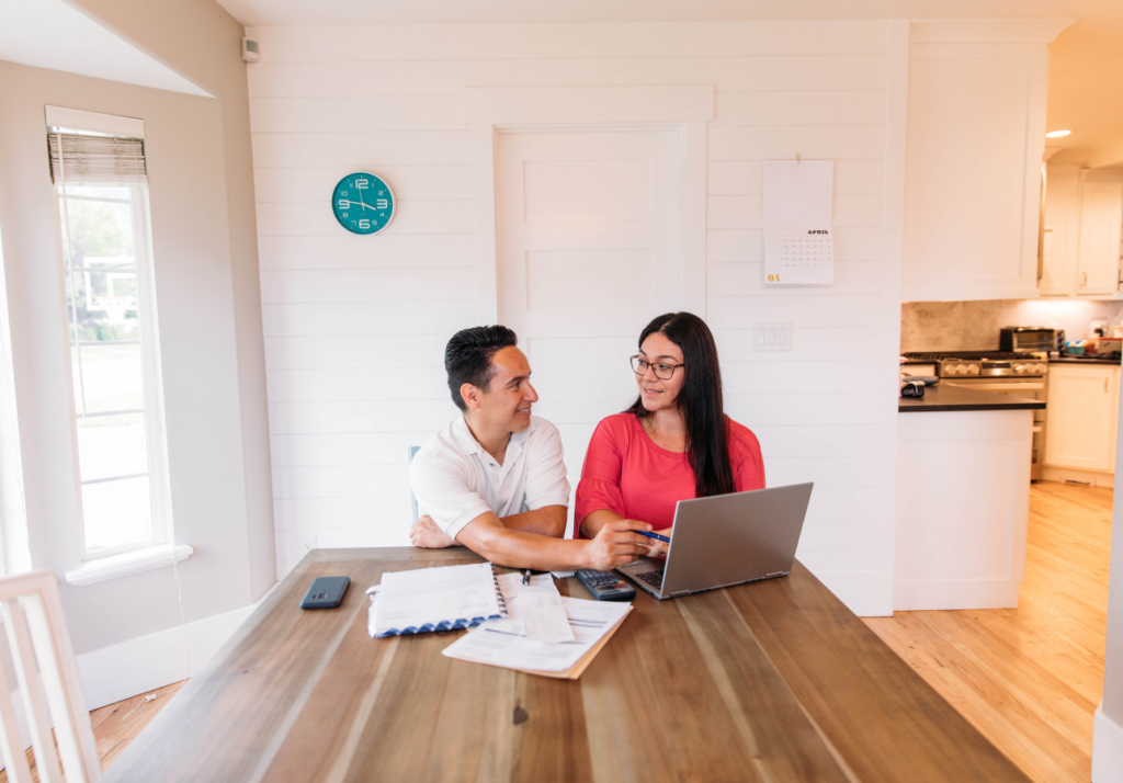 Canadian couple reviewing finances together at home with laptop and paperwork