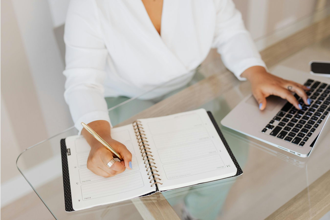 Person reviewing their automated finances in a planner alongside a laptop